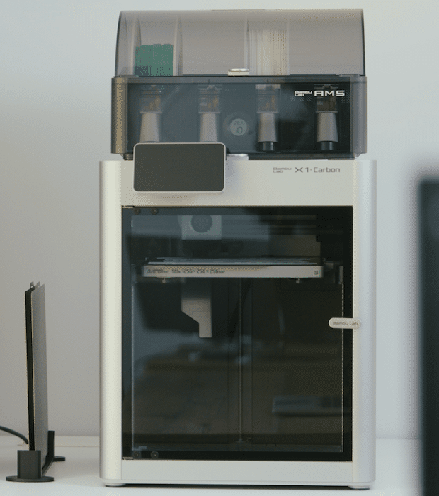 A high-tech X1 Carbon 3D printer with a transparent front and various components inside.