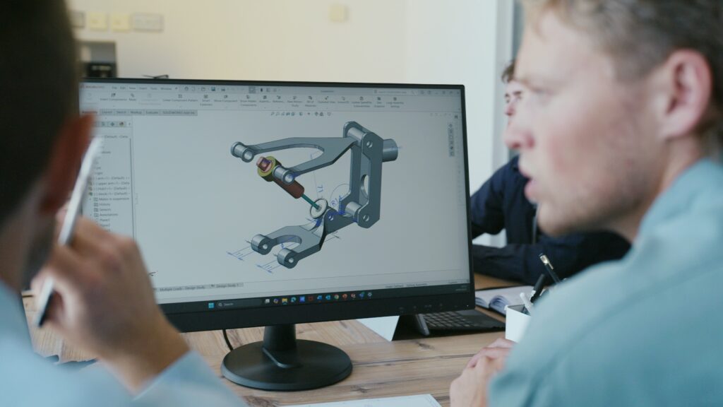 Person analyzing mechanical design on computer screen in office setting.