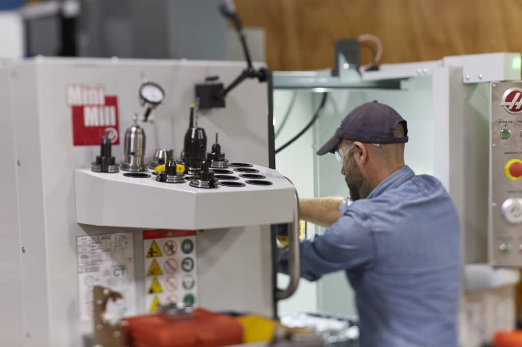 Man operating a 5-axis CNC machine at the Autodesk Technology Center Boston.