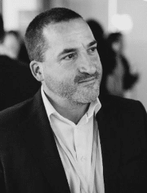 Man in a suit gazing to the side in a black and white setting.