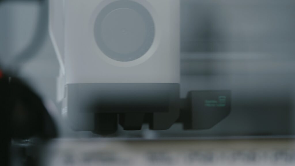 Close-up of a white industrial machine part with a circular component and displayed text, captured through glass.