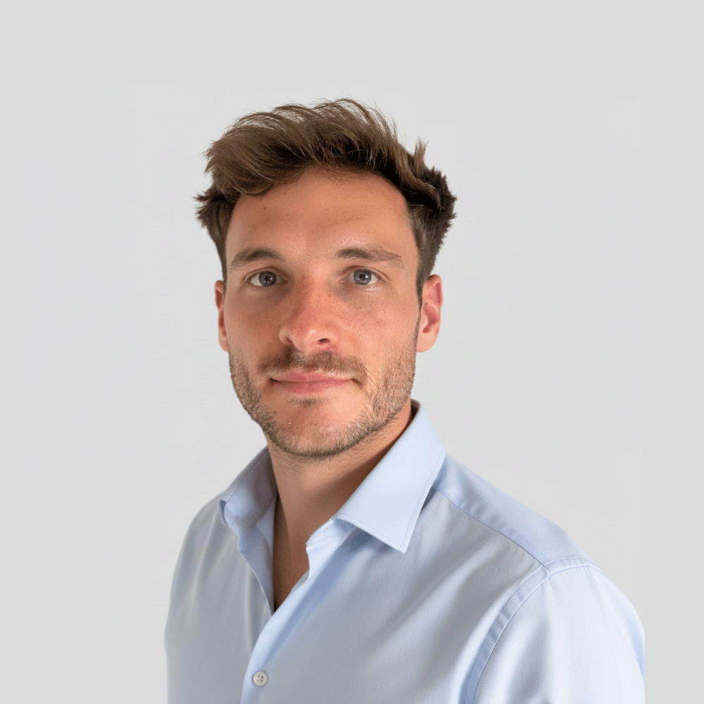 Portrait of a man in a light blue shirt against a plain background.